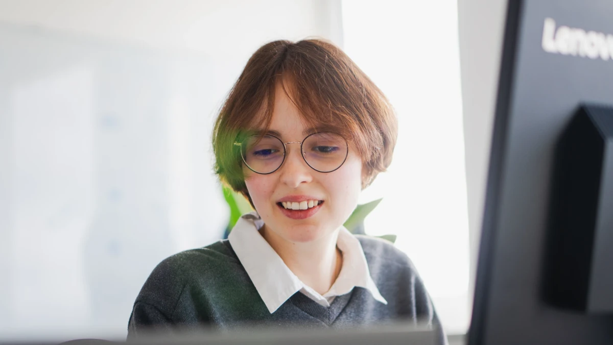 Eine junge Frau mit Brille und brauenen Haaren sitzt an einem Arbeitsplatz | SPIRIT/21