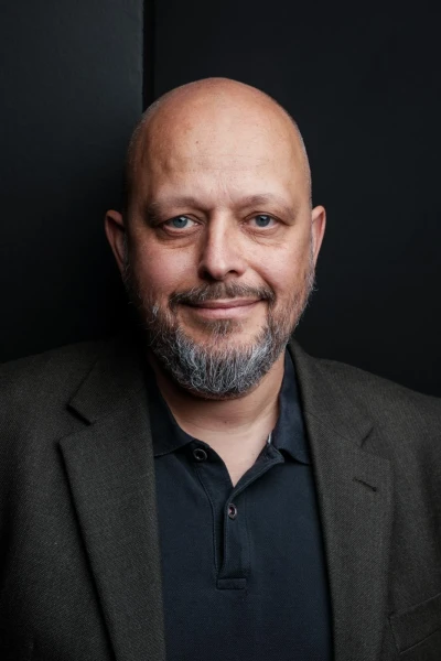 Studio-Portr&auml;t einer Person mit rasiertem Kopf und Bart vor dunklem Hintergrund im runden Bildausschnitt | SPIRIT/21